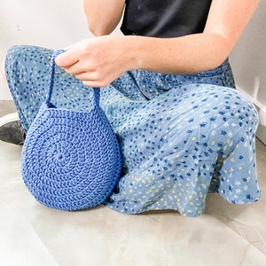 May include: A blue crocheted bag with a round shape and a single handle.