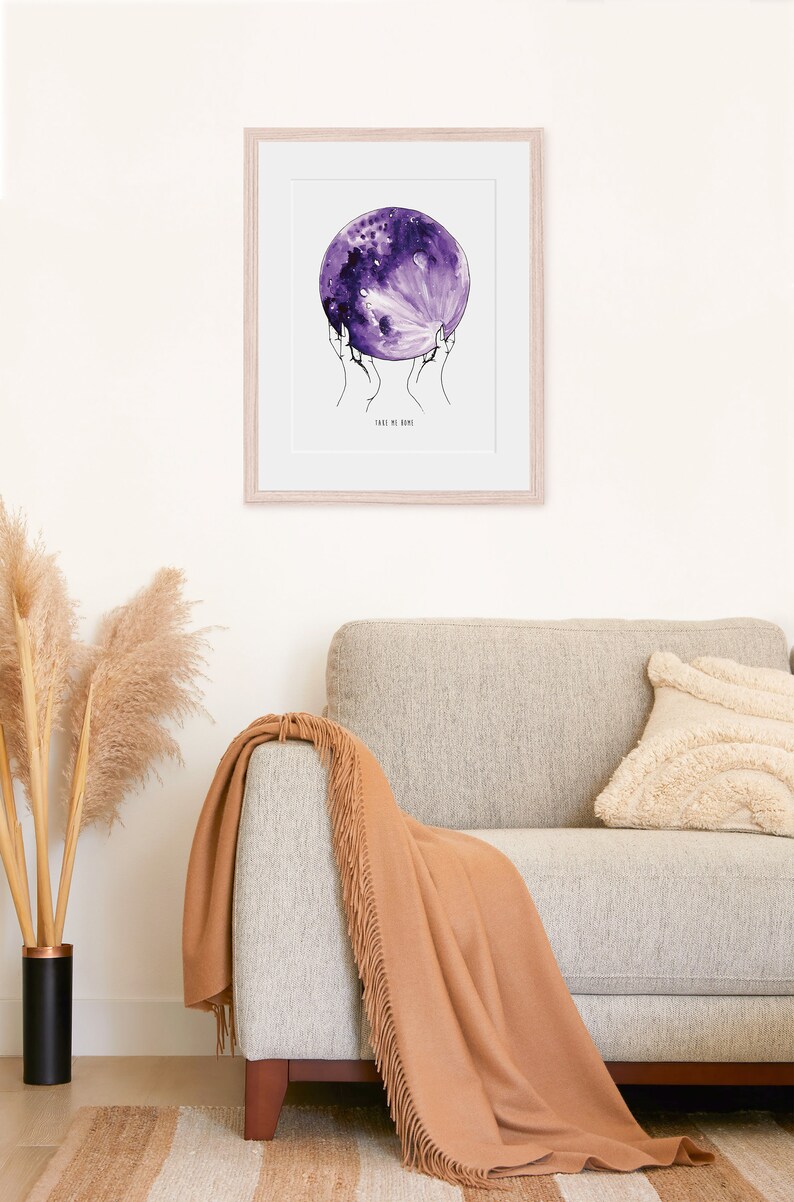 May include: A framed print of a watercolor painting of a purple moon being held by two hands. The text "Take me home" is written below the moon.