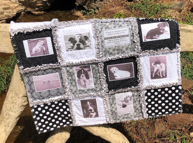 May include: A black and white quilt with a patchwork design featuring photos of dogs. The quilt has a quote about dogs in the center. "A dog is a whole lot of love wrapped in fur." "More than just a pet, they fill the heart and home with love."