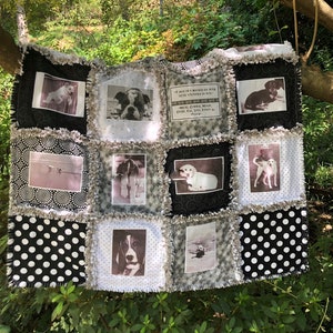 May include: A black and white quilt with a patchwork design featuring various dog photos and a quote about dogs. The quilt has a frayed edge and is made of cotton fabric.
