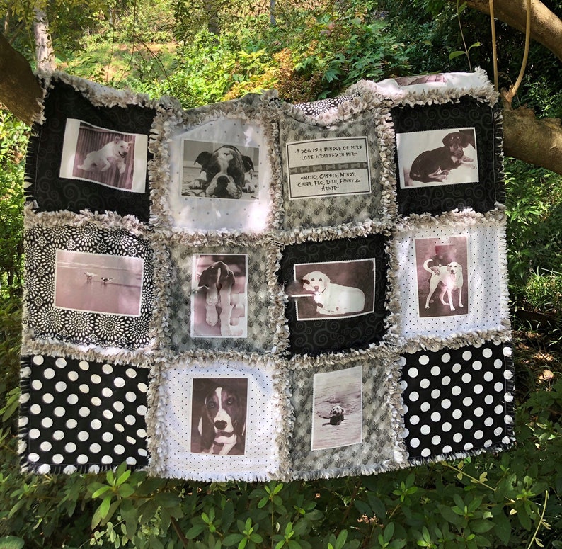 May include: A black and white quilt with a patchwork design featuring various dog photos and a quote about dogs. The quilt has a frayed edge and is made of cotton fabric.