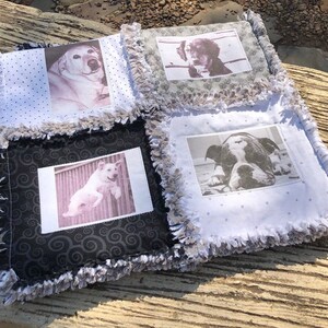 May include: A handmade quilt with four squares featuring black and white photos of dogs. Each square has a different patterned fabric background. The quilt has a frayed edge.