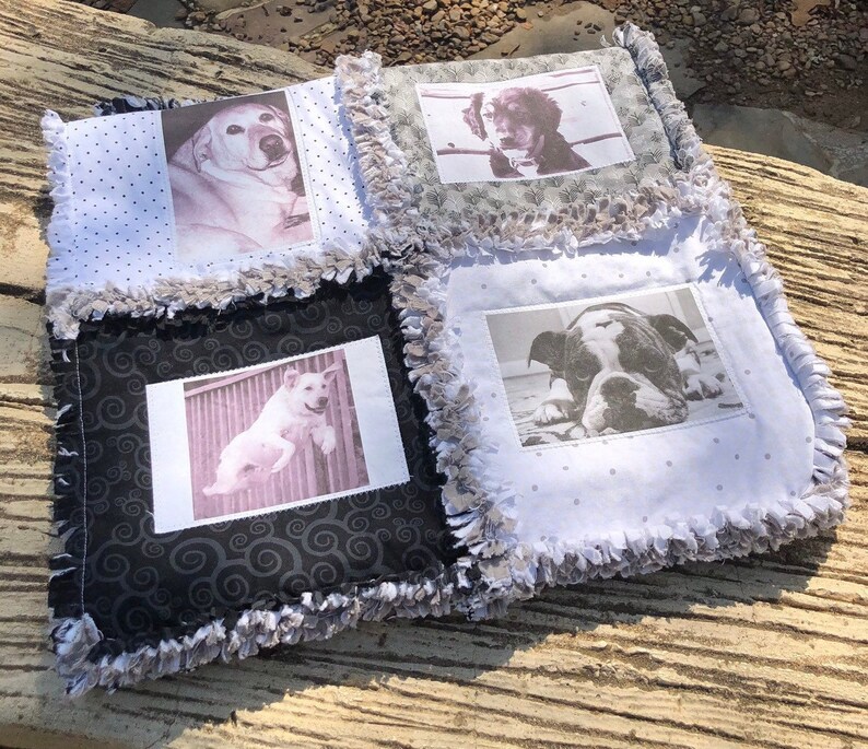 May include: A handmade quilt with four squares featuring black and white photos of dogs. Each square has a different patterned fabric background. The quilt has a frayed edge.