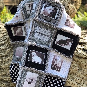 May include: A black and white quilt with a patchwork design featuring photos of dogs and a quote about dogs. The quilt has a black and white polka dot pattern on the bottom.