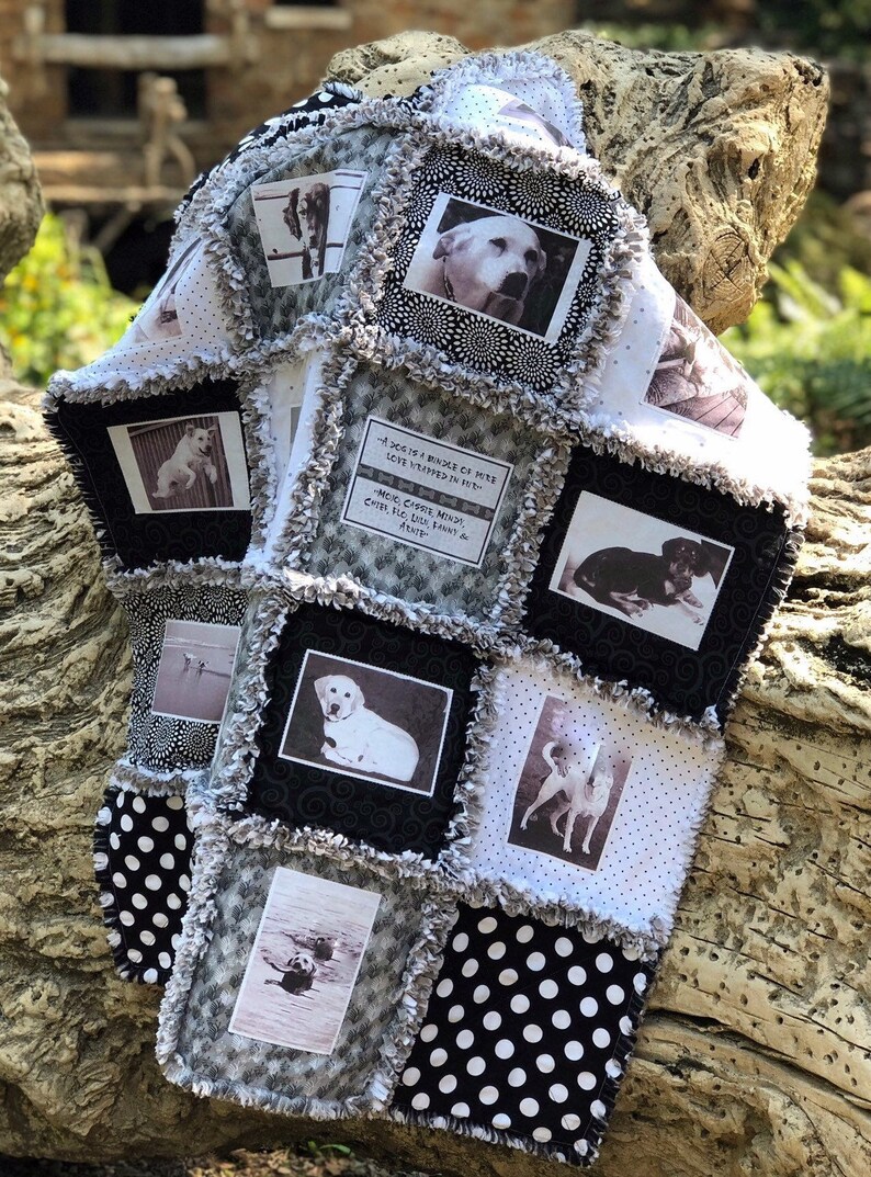 May include: A black and white quilt with a patchwork design featuring photos of dogs and a quote about dogs. The quilt has a black and white polka dot pattern on the bottom.