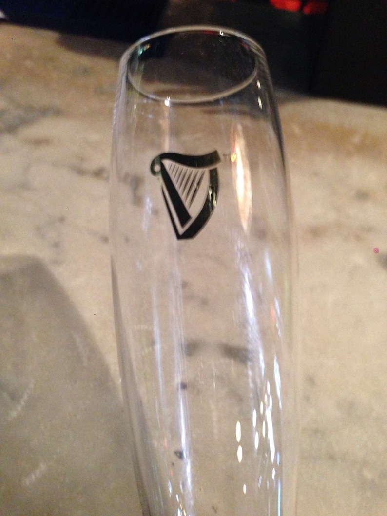 Op de afbeelding: Een heldere glazen champagnefluit met een zwart-wit harplogo aan de zijkant.