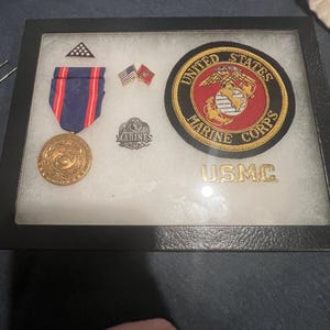 United States Marine Corps display case with medal pins and patch