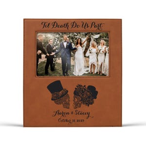 Op de afbeelding: Een bruin lederen fotolijst met een trouwfoto. De lijst is voorzien van de tekst "Til Death Do Us Part" en heeft suikerschedelontwerpen. De namen "Aaron & Stacey" en de datum "October 31, 2027" zijn ook opgenomen.