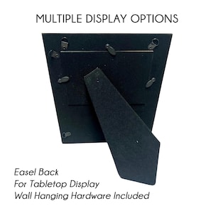 Op de afbeelding: Zwarte achterkant van een fotolijst met ezel en ophangmateriaal. De tekst luidt "Multiple Display Options", "Easel Back", "For Tabletop Display" en "Wall Hanging Hardware Included".