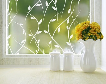 May include: White ceramic jars and a vase with yellow flowers, sitting on a wooden surface in front of a window with a frosted glass pane featuring a white vine pattern.