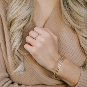 Woman wearing 14k gold filled hammered beaded ring and 14k gold filled ultra thin gold ring and various other Laurel Elaine Jewelry