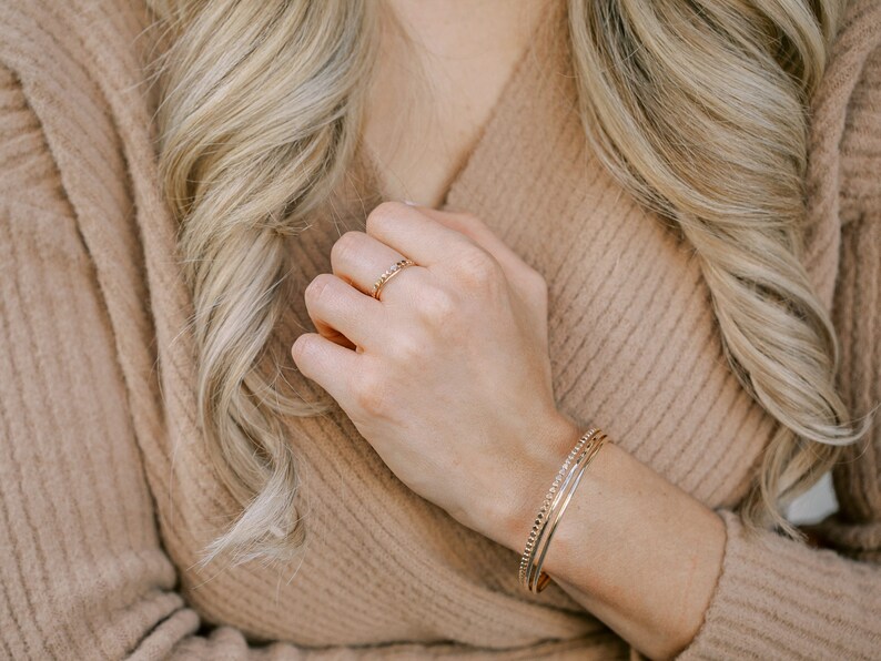 Woman wearing 14k gold filled hammered beaded ring and 14k gold filled ultra thin gold ring and various other Laurel Elaine Jewelry