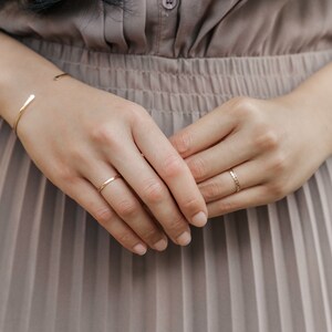 Woman wearing 14k gold filled hammered beaded ring and 14k gold filled ultra thin gold ring and various other Laurel Elaine Jewelry