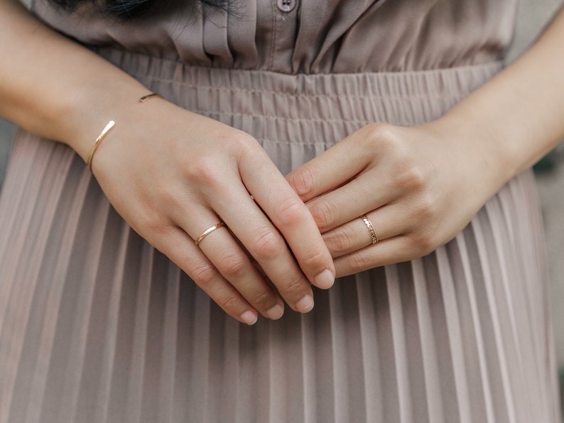 Woman wearing 14k gold filled hammered beaded ring and 14k gold filled ultra thin gold ring and various other Laurel Elaine Jewelry