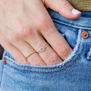 Woman wearing 14k gold filled and sterling silver interlocking double knot ring and various other Laurel Elaine Jewelry
