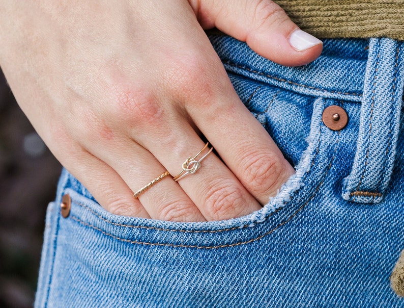 Woman wearing 14k gold filled and sterling silver interlocking double knot ring and various other Laurel Elaine Jewelry