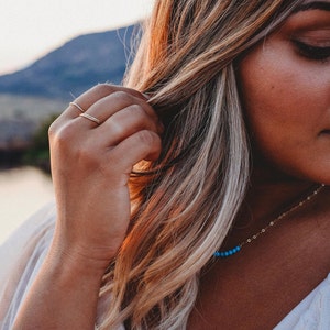 Woman wearing 14k gold filled ultra thin rings and various other Laurel Elaine Jewelry