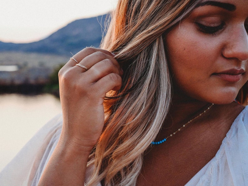 Woman wearing 14k gold filled ultra thin rings and various other Laurel Elaine Jewelry