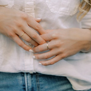 Woman wearing 14k gold filled knot ring and various other Laurel Elaine Jewelry