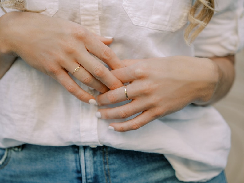 Woman wearing 14k gold filled knot ring and various other Laurel Elaine Jewelry