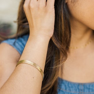 Woman wearing set of three thick gold bangles