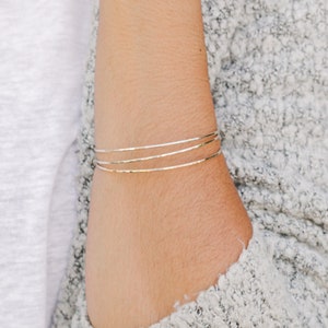 Woman wearing a set of three 14k gold filled bangles