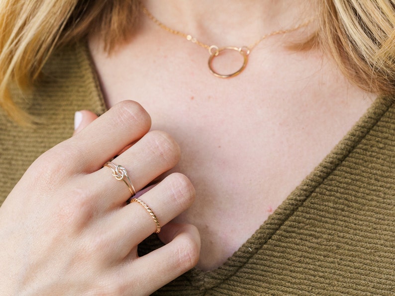 Woman wearing 14k gold filled and sterling silver interlocking double knot ring and various other Laurel Elaine Jewelry