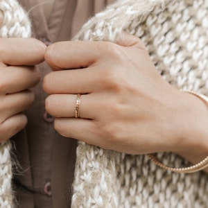 Woman wearing 14k gold filled ultra thin rings and various other Laurel Elaine Jewelry