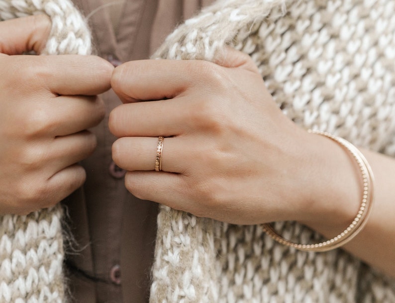 Woman wearing 14k gold filled ultra thin rings and various other Laurel Elaine Jewelry