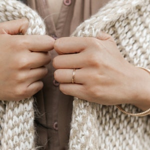 Woman wearing 14k gold filled hammered beaded ring and 14k gold filled ultra thin gold ring and various other Laurel Elaine Jewelry