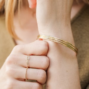 Woman wearing thick gold bangles and other gold filled jewelry