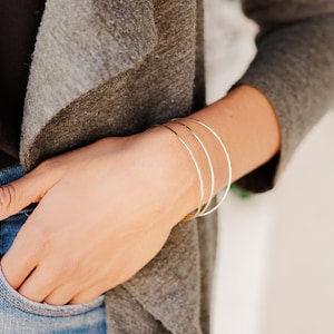 Woman wearing a set of three 14k gold filled bangles