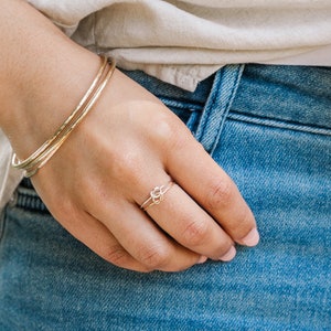 Woman wearing thick gold bangles and other gold filled jewelry