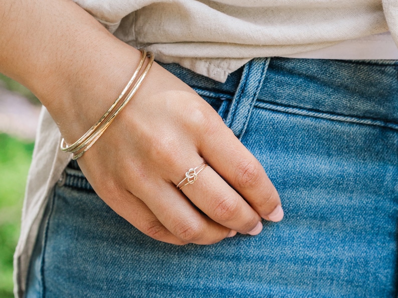 Woman wearing thick gold bangles and other gold filled jewelry