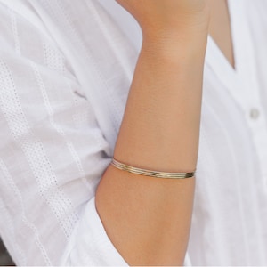 Woman wearing a set of three 14k gold filled bangles