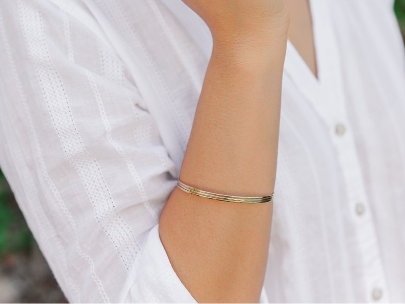 Woman wearing a set of three 14k gold filled bangles