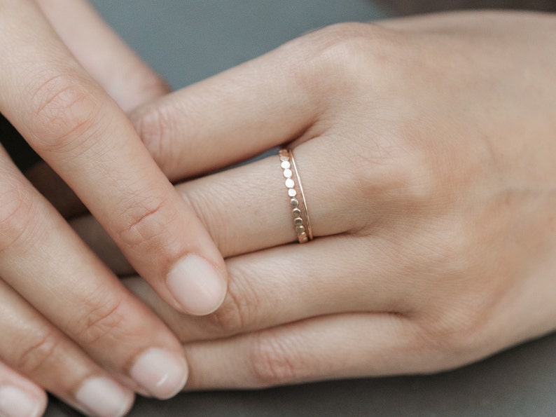 Woman wearing 14k gold filled hammered beaded ring and 14k gold filled ultra thin gold ring