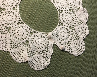 May include: White crocheted collar with a scalloped edge and two white buttons.