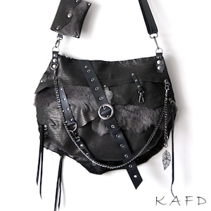 Puede incluir: Un bolso de hombro de cuero negro con una peque&ntilde;a bolsa desmontable. El bolso presenta un dise&ntilde;o &uacute;nico con texturas en capas, herrajes met&aacute;licos y un detalle de cadena. El bolso tiene una correa larga ajustable. La marca "KAFDERRY" est&aacute; impresa en la parte inferior.