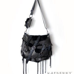 May include: Black leather shoulder bag with a layered design, featuring a small attached pouch. The bag has a long adjustable strap, metal hardware, and decorative fringe. The word "KAFDERRY" is printed at the bottom.