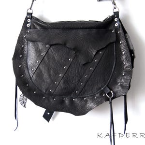 Puede incluir: Bolso de hombro de cuero negro con remaches plateados y un bolsillo con solapa. El bolso tiene un dise&ntilde;o texturizado &uacute;nico y largas borlas negras. La marca "KAFDERRY" est&aacute; impresa en la parte inferior.
