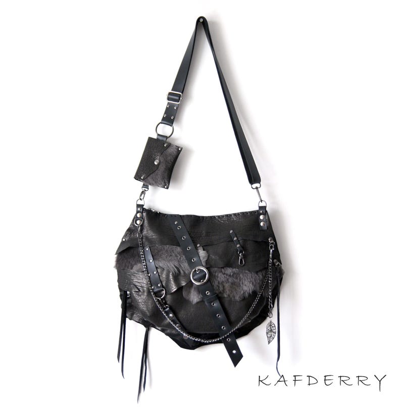 Puede incluir: Un bolso de hombro de cuero negro con una peque&ntilde;a bolsa desmontable. El bolso presenta un dise&ntilde;o &uacute;nico con texturas en capas, herrajes met&aacute;licos y un detalle de cadena. El bolso tiene una correa larga ajustable. La marca "KAFDERRY" est&aacute; impresa en la parte inferior.