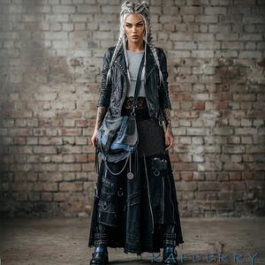 以下が含まれることがあります： 黒い革のジャケット、グレーのトップス、ポケットとジッパー付きの長い黒いスカートを着た人。黒と青のショルダーバッグが左側にぶら下がっています。この服装はゴシック、パンク、または代替的な美学を持っています。