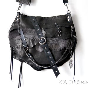 Puede incluir: Bolso de hombro de cuero negro con un dise&ntilde;o en capas y una cadena plateada. El bolso presenta una correa con un anillo de metal y un dije de hoja decorativa. La palabra "KAFDERRY" est&aacute; impresa en negro.