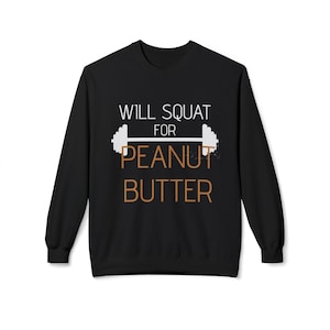 Puede incluir: Sudadera negra de cuello redondo con el texto "WILL SQUAT FOR PEANUT BUTTER" en blanco y marrón. El diseño incluye una barra con pesas. Una prenda superior informal y cómoda para los entusiastas del fitness.