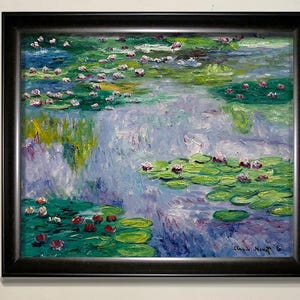 以下が含まれることがあります： クロード・モネによる睡蓮の額入り絵画。この作品は、緑、青、紫、赤の色合いのスイレンと花のある池を描いています。絵画は黒いフレームに入っており、白い壁に展示されています。