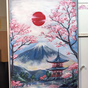 May include: A hand-painted scroll depicting a Japanese landscape with Mount Fuji, a red sun, cherry blossoms, a pagoda, and a lake. The scroll is framed with a dark wood frame and a blue and gold patterned border.