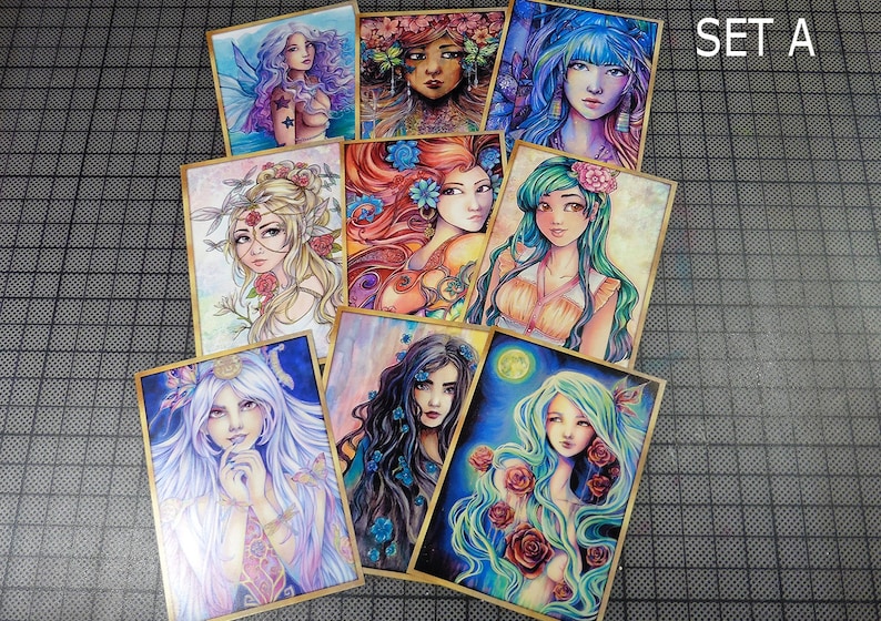 May include: Set of eight illustrated cards featuring colorful portraits of women with floral accents. The cards are framed with a gold border and have a textured surface. The cards are labeled "SET A" in the top right corner.