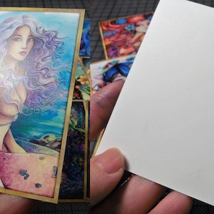 May include: A colorful illustration of a mermaid with long purple hair and a blue tail. The mermaid is surrounded by water and stars. The illustration is framed in gold.