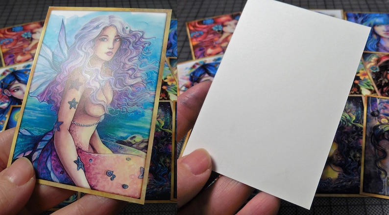 May include: A colorful illustration of a mermaid with long purple hair and a blue tail. The mermaid is surrounded by water and stars. The illustration is framed in gold.